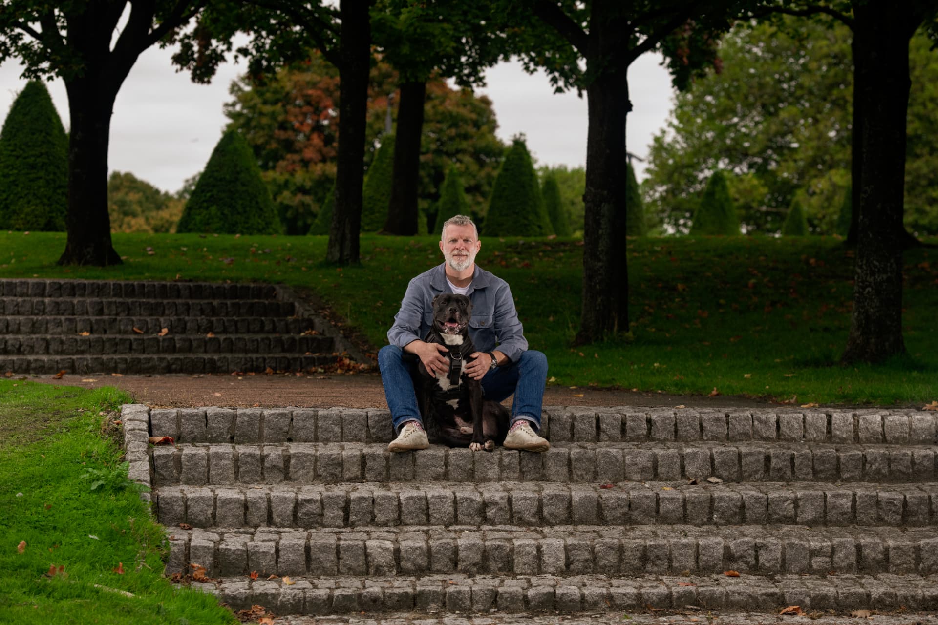 Relaxed dog and trainer sitting together on stone steps in a Glasgow park
