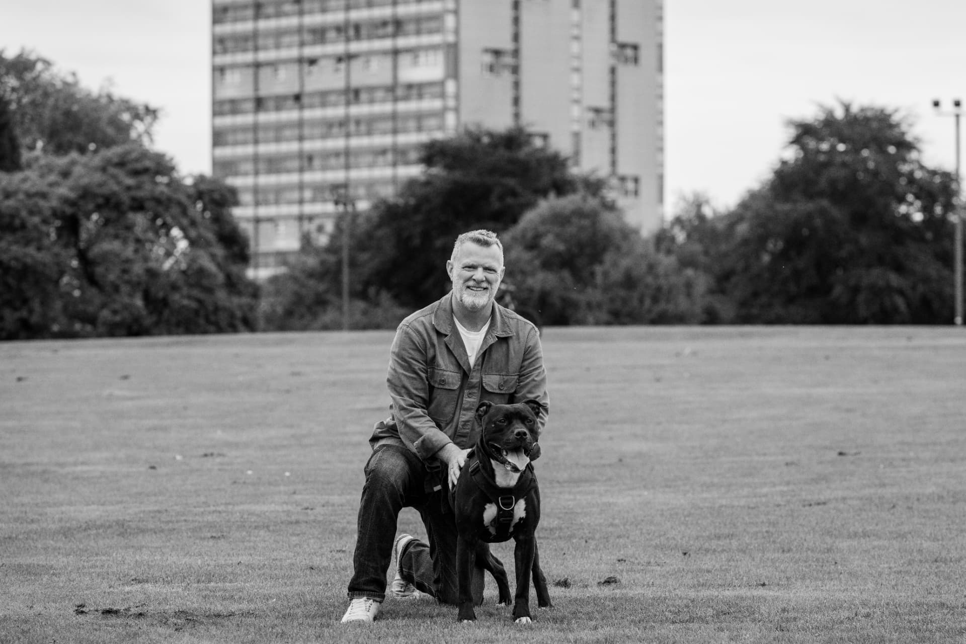 Black and white portrait of Glasgow dog trainer John McGuigan with a black Labrador