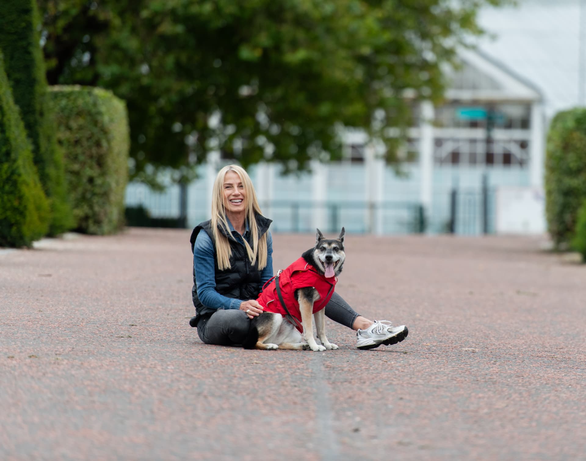 Trainer sitting on a park path beside a settled dog in Glasgow