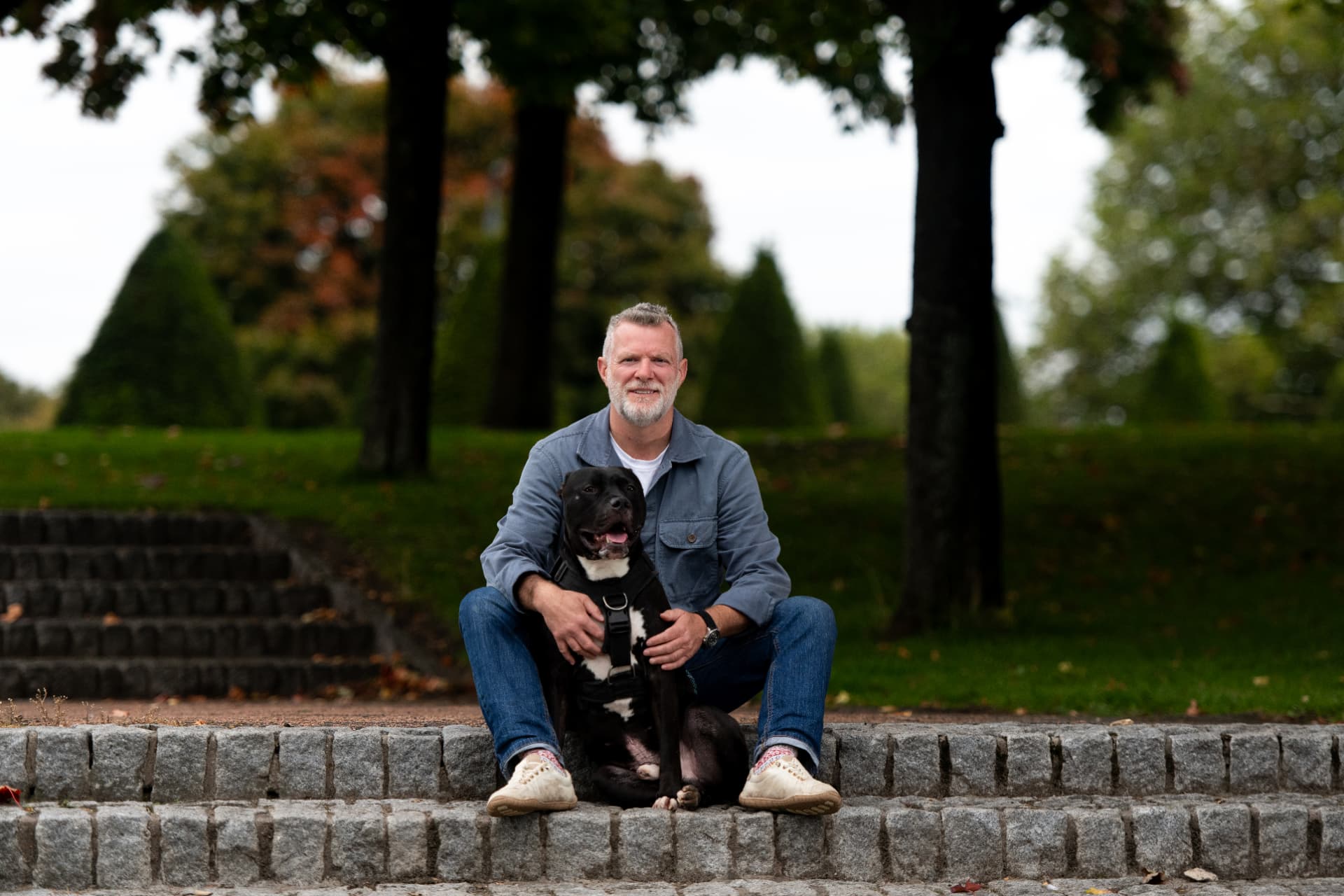 Glasgow dog trainer John McGuigan sitting on park steps with two settled dogs