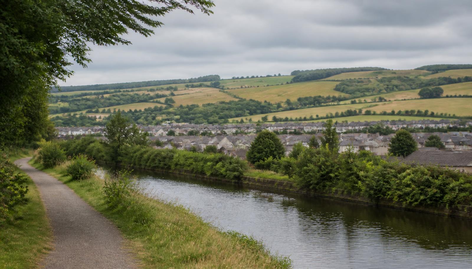 North Lanarkshire canal towpath with farmland and a residential town beyond